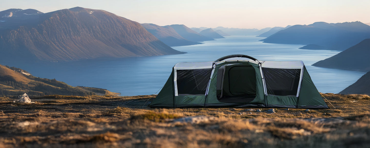 Tent set up on a mountainous landscape with a lake and mountains in the background