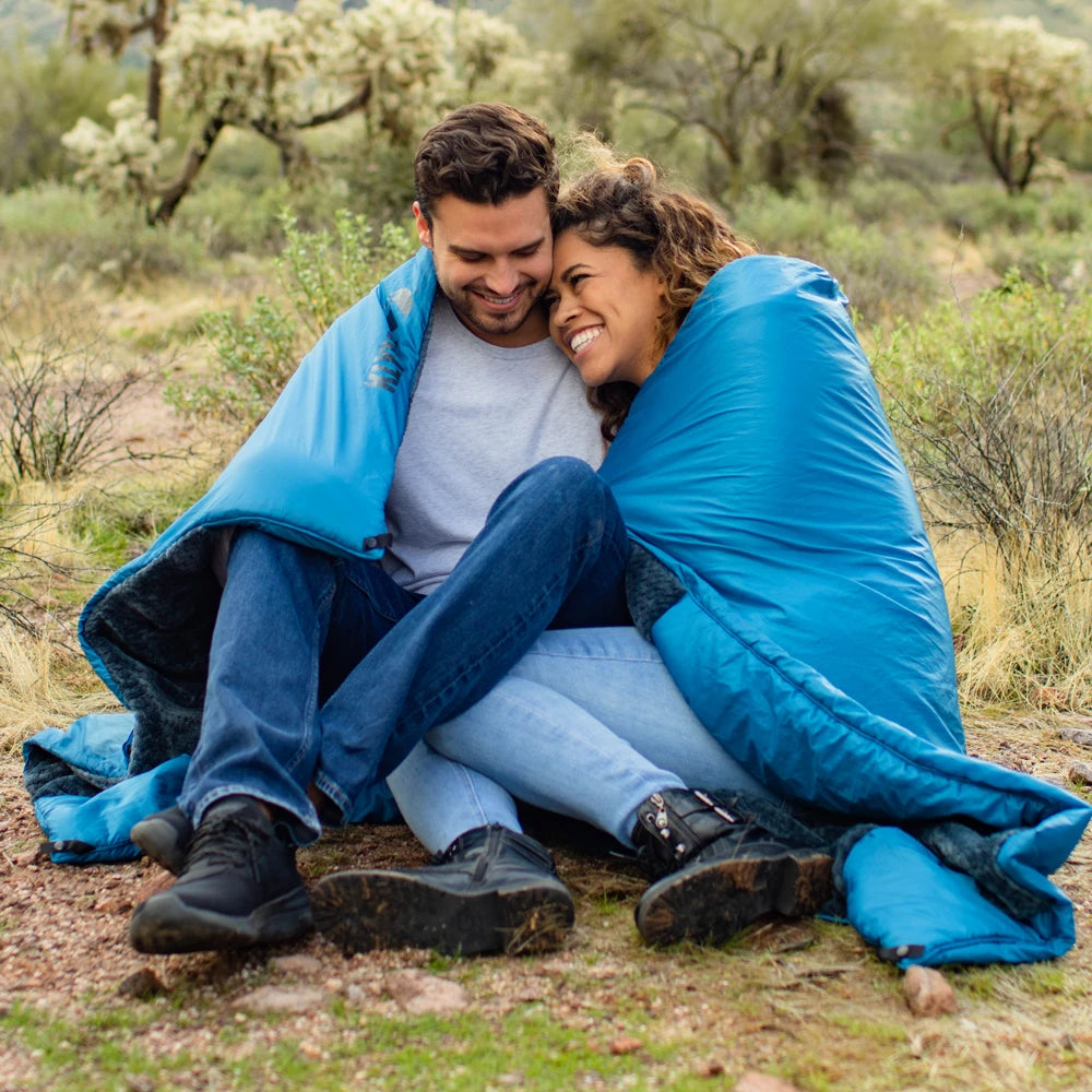 Couple sitting together under a blue blanket in a desert setting