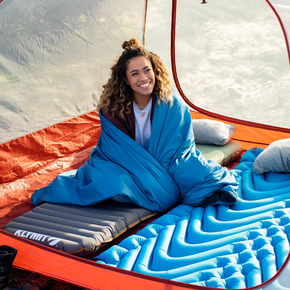 Woman wrapped in a blue sleeping bag inside a tent
