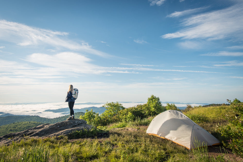 woman hiking on mountain with an outdoor connection hiking tent