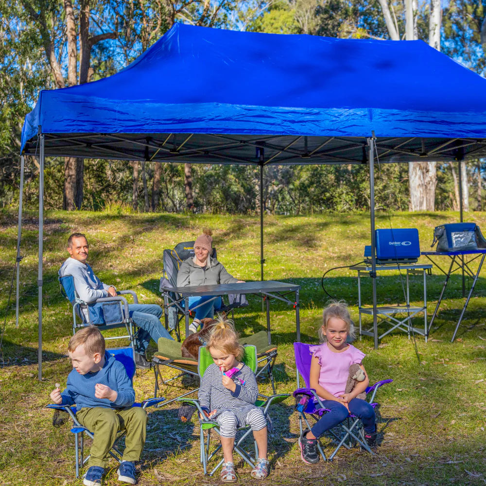 family camping under a gazebo in chairs and a table and stove